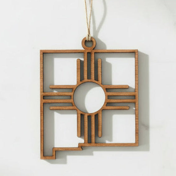 Laser-cut wooden New Mexico Zia Sun ornament with hanging cord and natural wood finish.